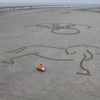 Those posts embedded in the sand help the robot orient its position as well as the picture placement.