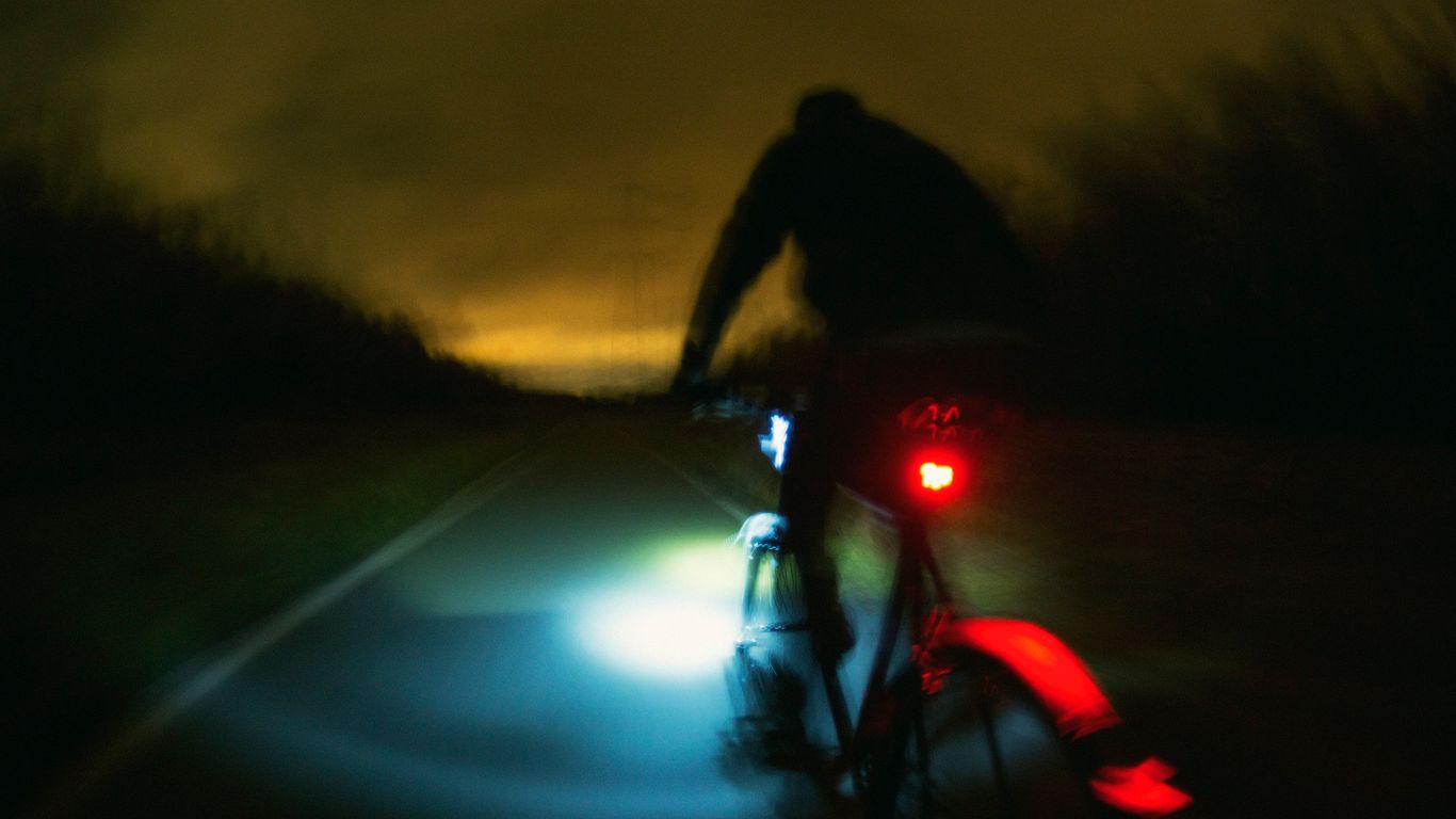 a man riding a bike down a street at night