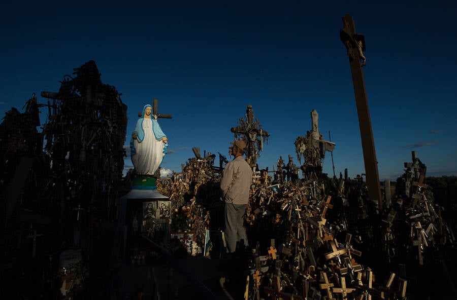 Man Praying In Front Of Virgin Mary Statue