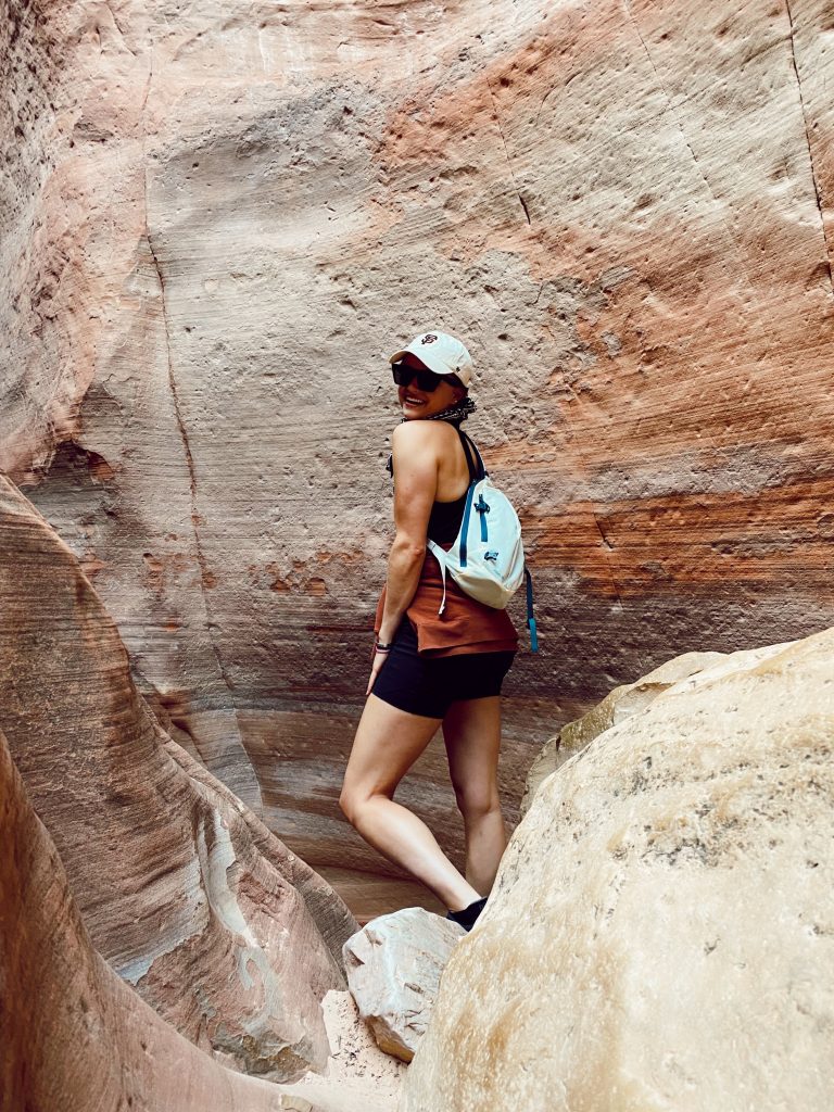 girl standing in front of a mountain cave smiling