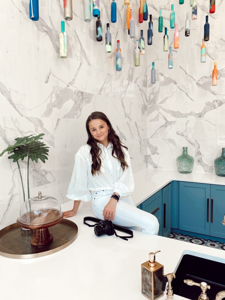 girl sitting on the counter with a camera on her lap and smiling