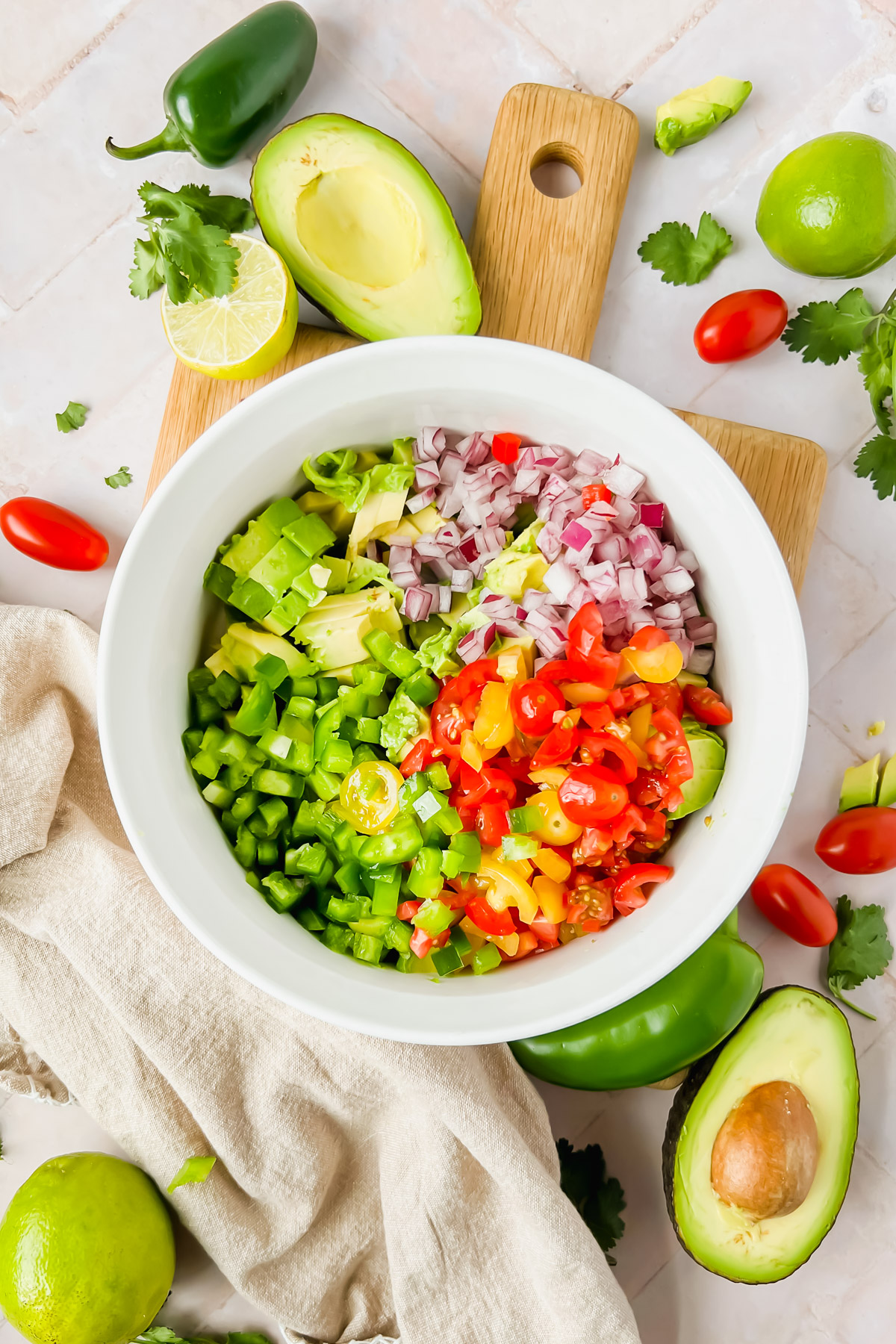 ingredients for avocado crack dip chopped and placed in white bowl before tossing.