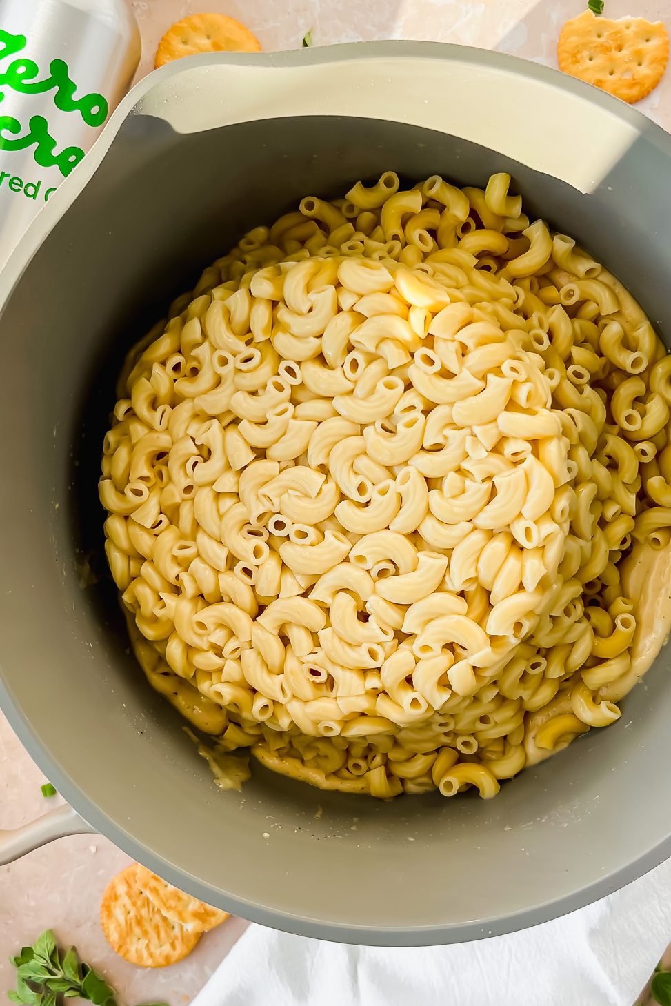 tan pot full of elbow noodles beside bottle of Zero Acre cultured oil.