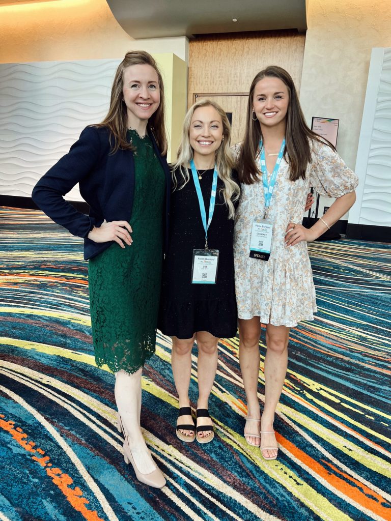 three ladies in dresses smiling after a convention briefing. 