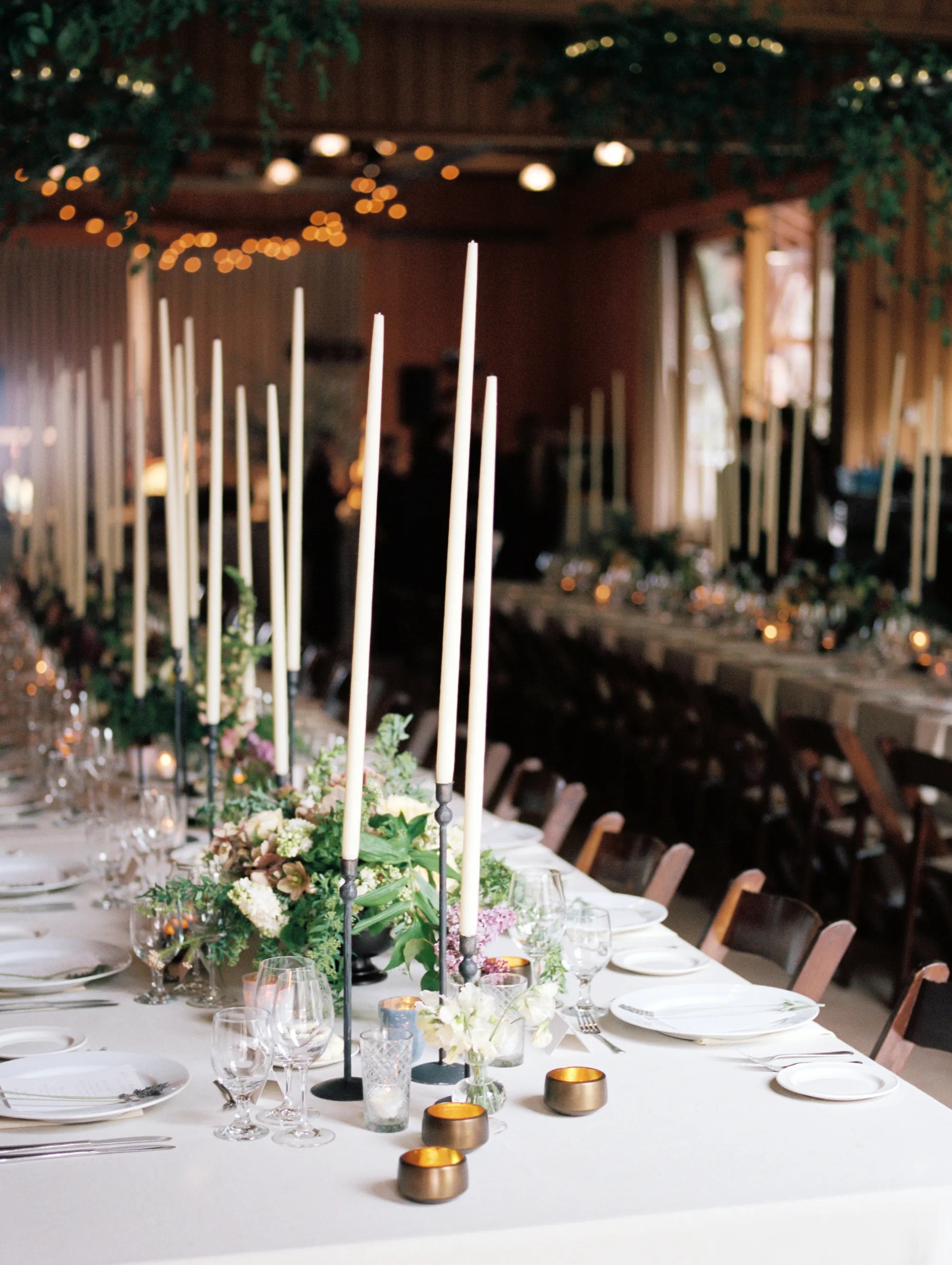 Dining tables with tall white candle centerpieces