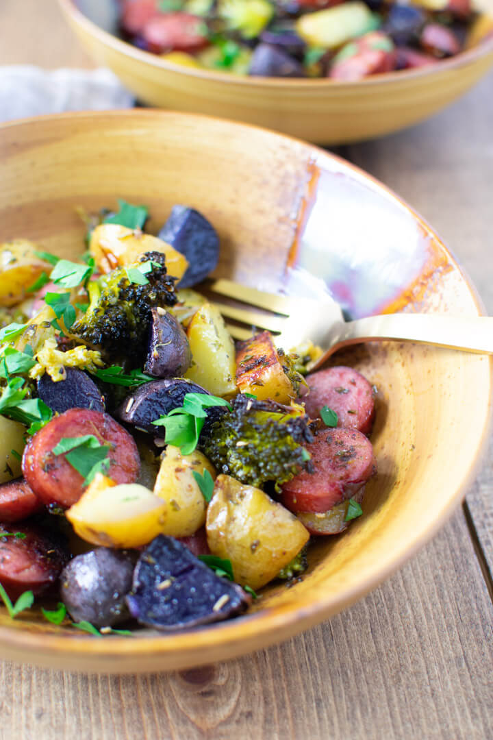 Closeup of smoked sausage and potatoes and veggies in a bowl with a fork
