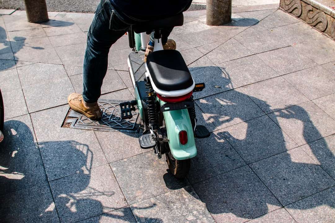 person in black jacket riding white and green motor scooter Puzzle