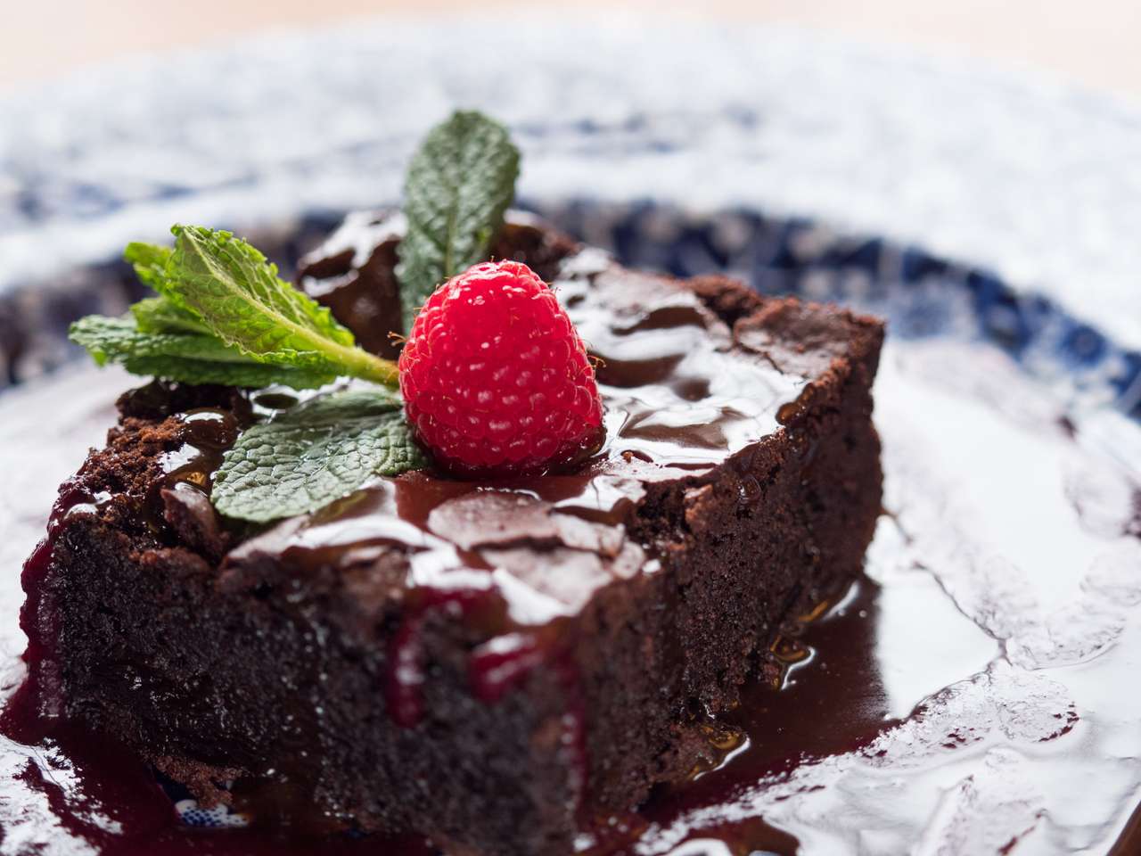 CLOSE UP SLICE OF CHOCOLATE CAKE SERVED ON A PLATE WITH CHOCOLATE SAUCE