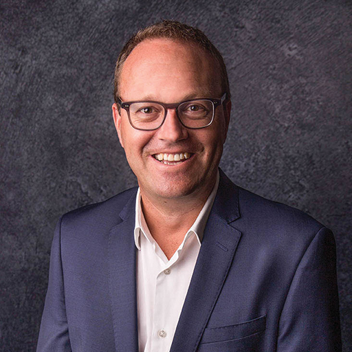 A man wearing glasses and a suit, smiling at Atlantis Beach.