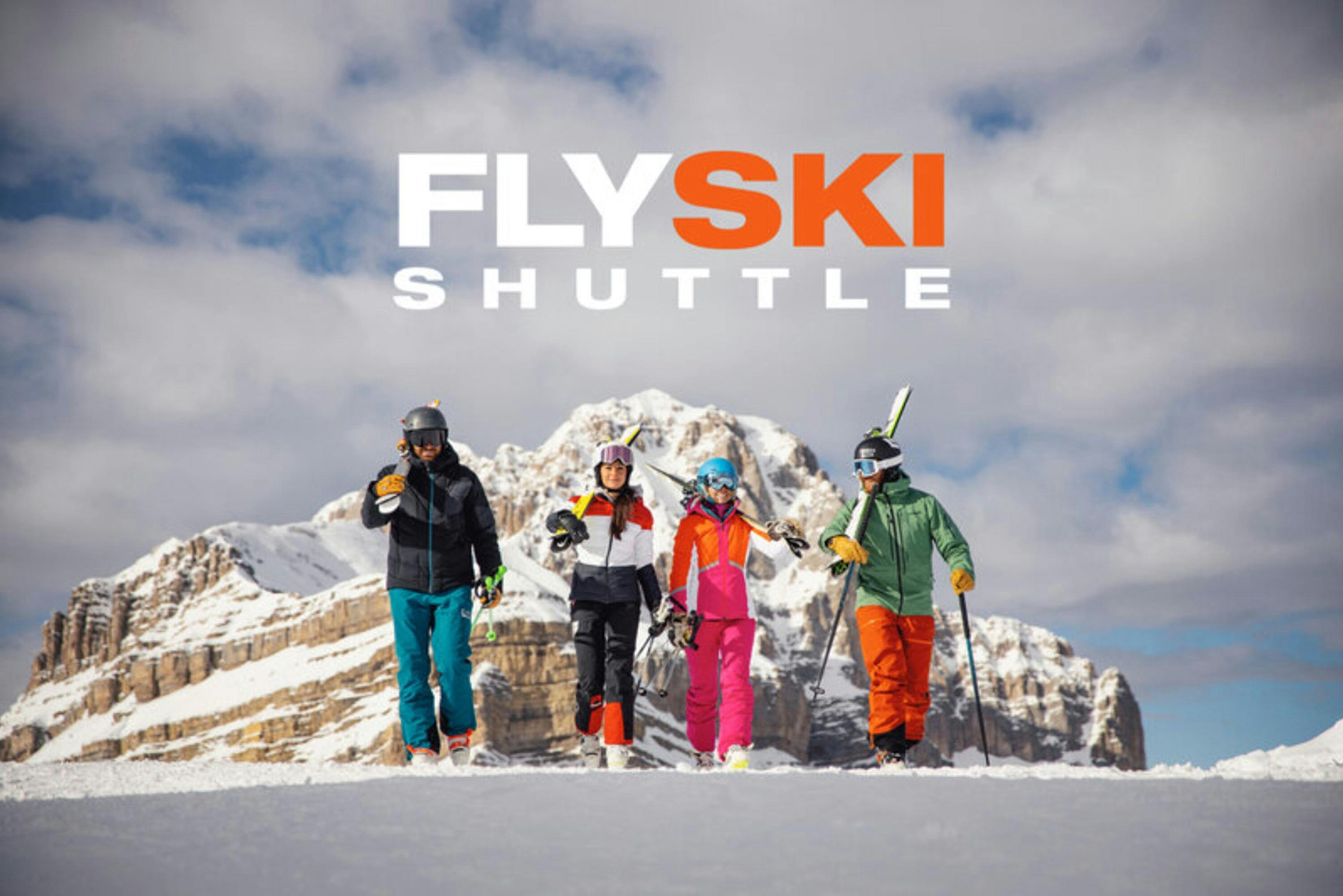 Four skiers in colorful outfits walk on a snow-covered mountain with "FLY SKI SHUTTLE" text above them.