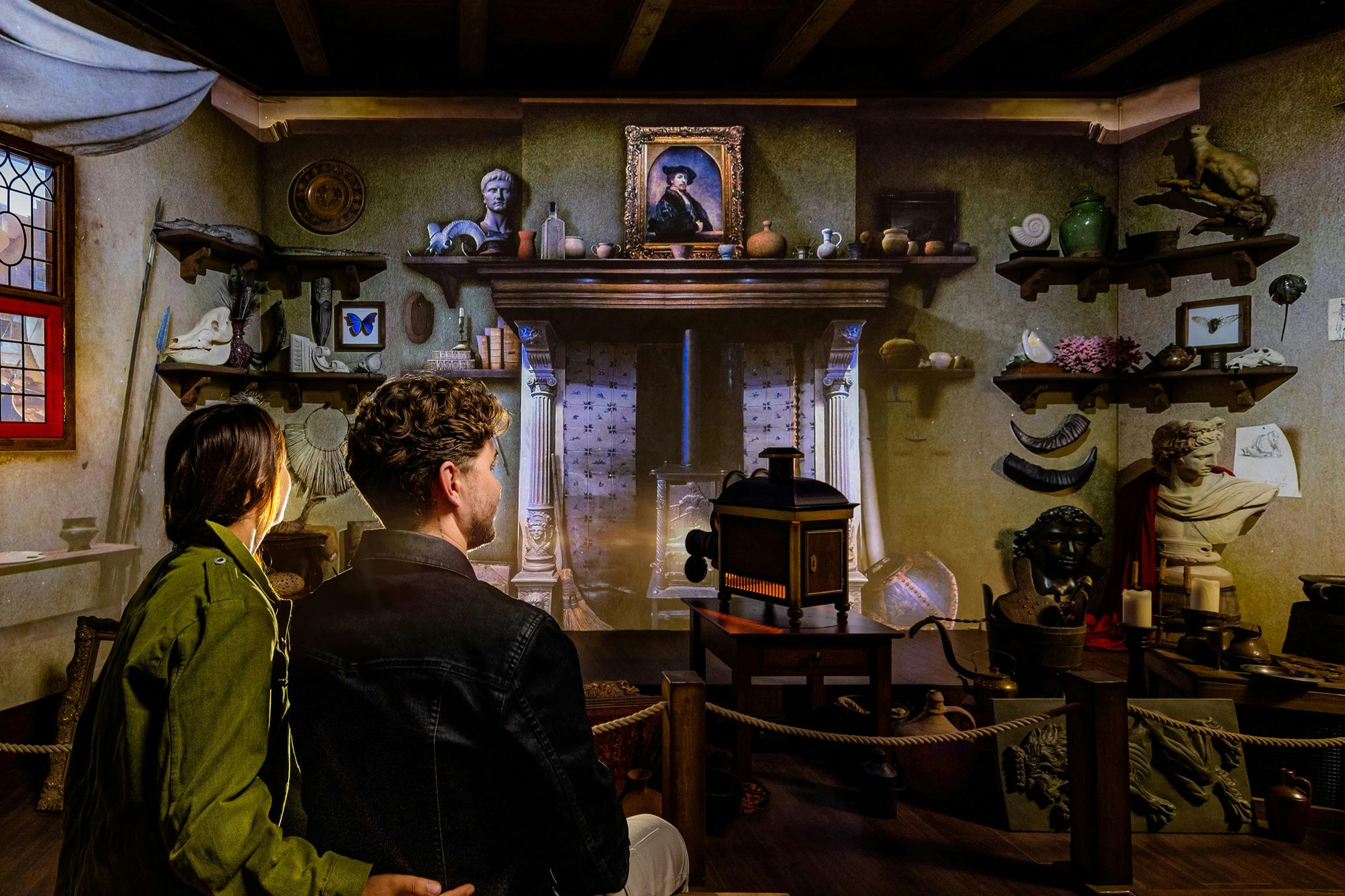 Two people observe a detailed room exhibit featuring an antique fireplace, shelves with artifacts, and a framed portrait above the mantle.