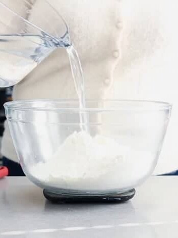 Pouring water into a bowl of flour