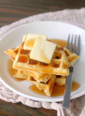 A stack of waffles with syrup and butter