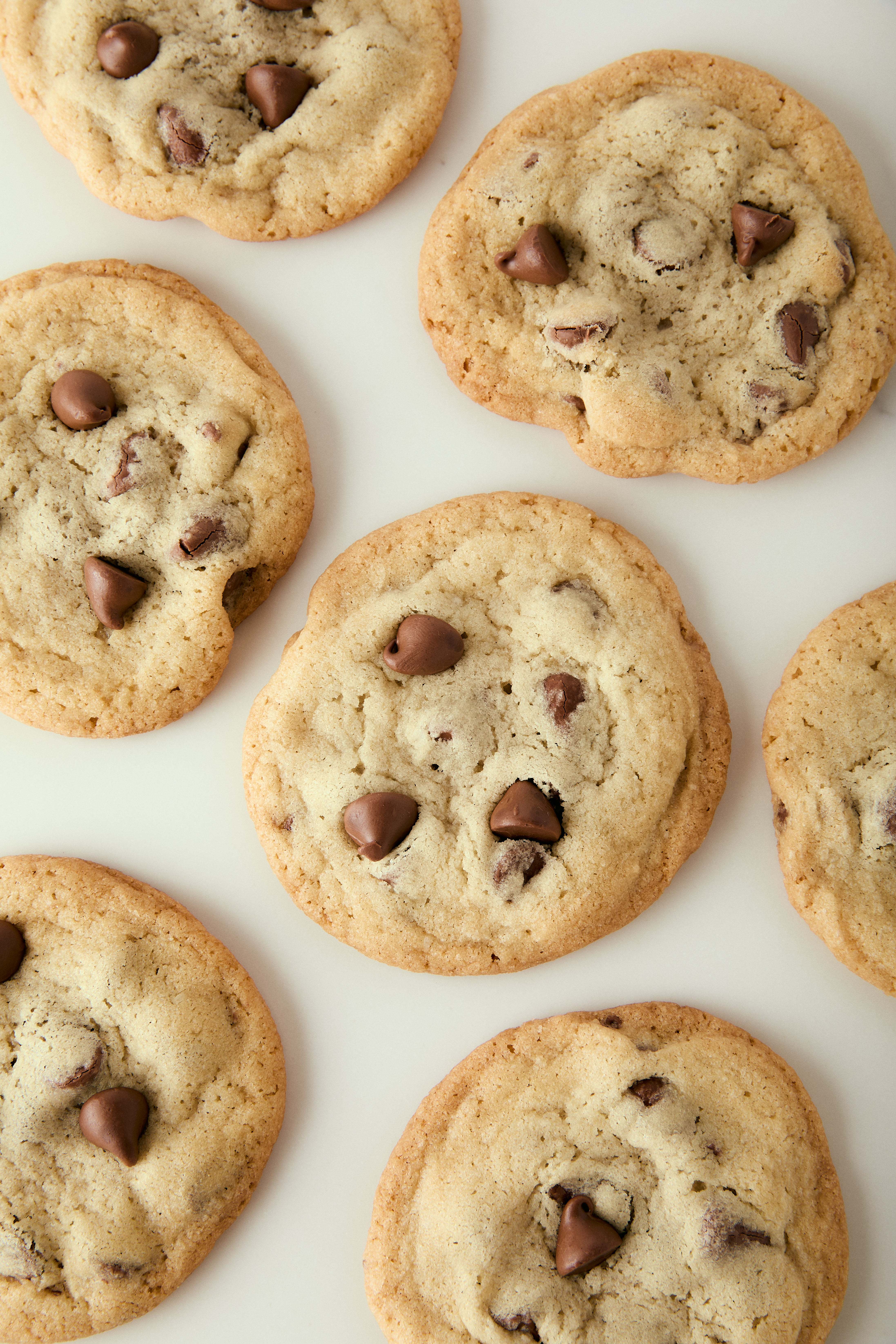 Thin and Crispy Chocolate Chip Cookies- Baker Bettie thin and crispy cookies spread on a counter