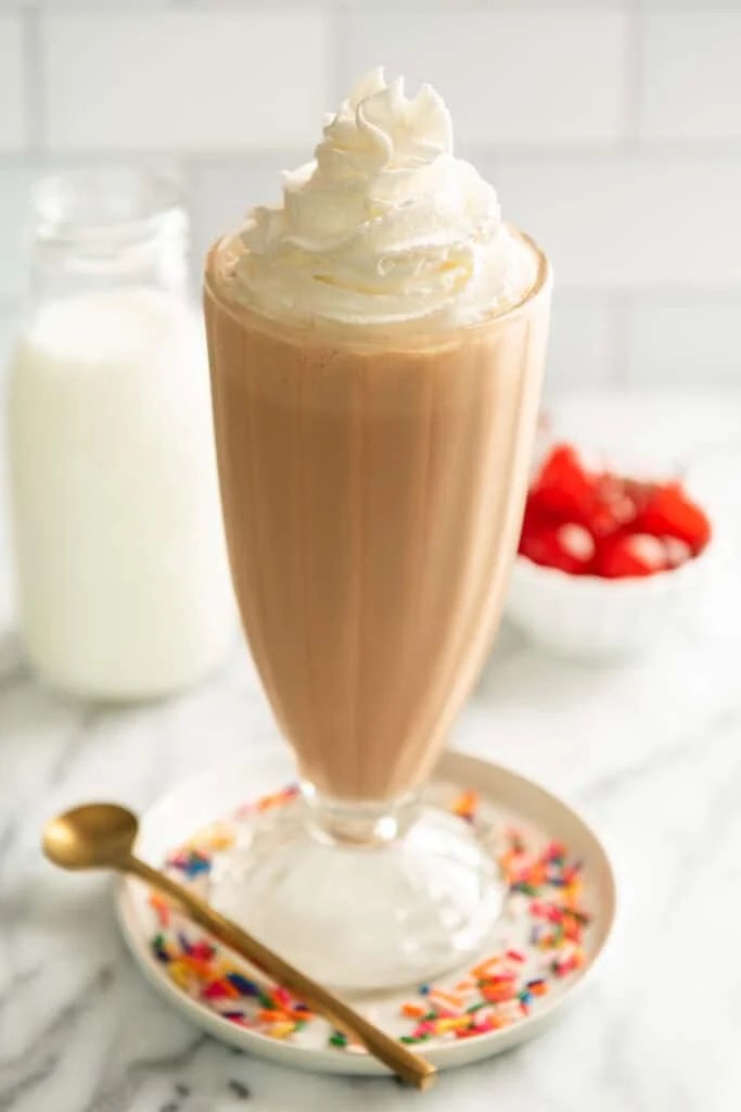 Malted milkshake in a glass with whipped cream.