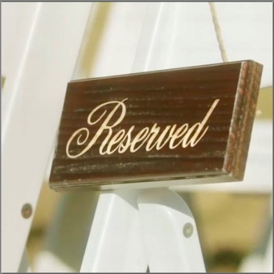 Wooden reserve signs for front row wedding chairs.