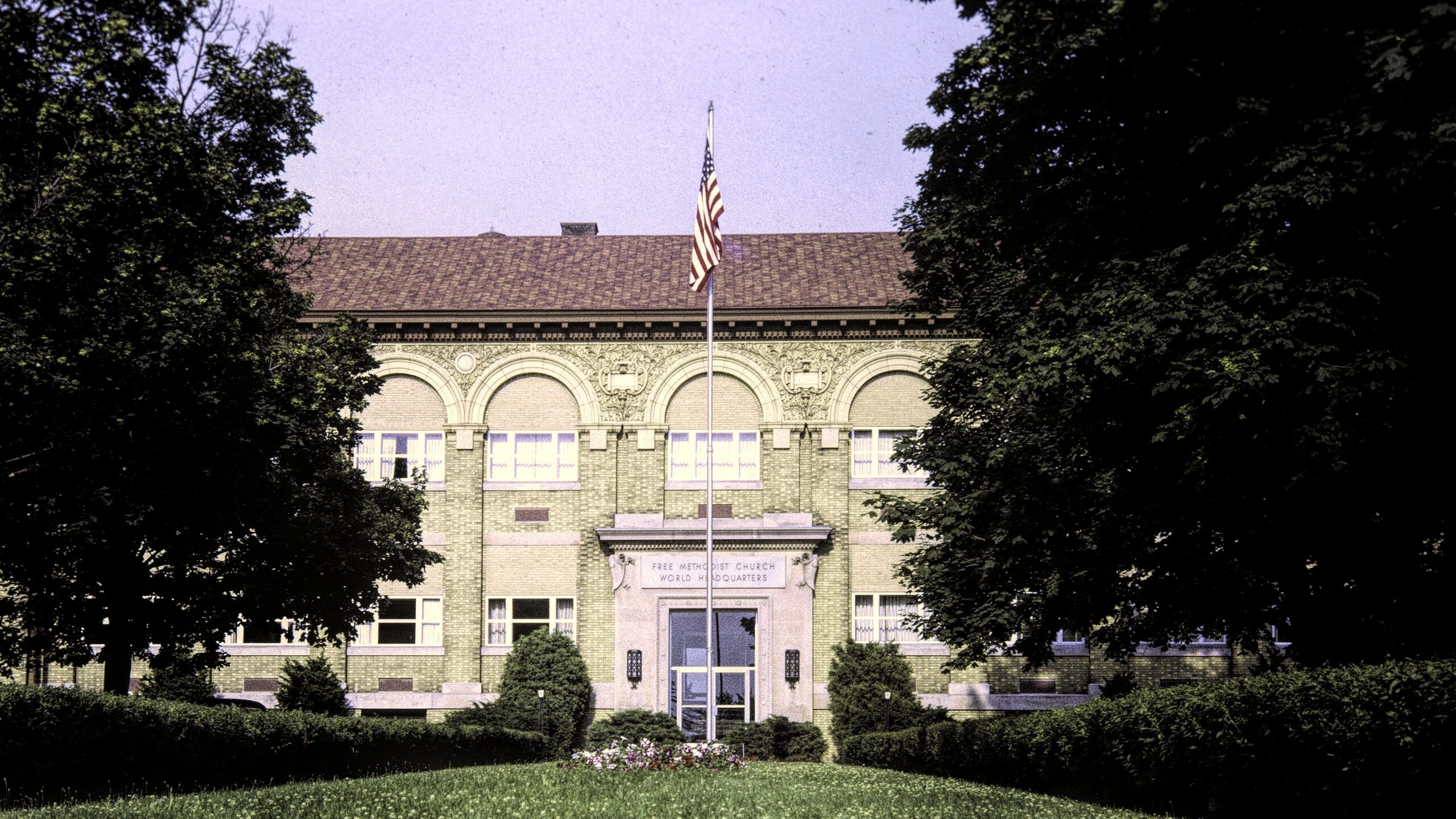 A large older brick bilding with a flag pole in front of it