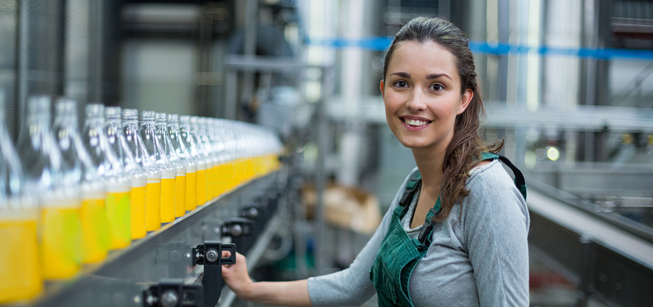 Portrait of female factory worker standing near production line