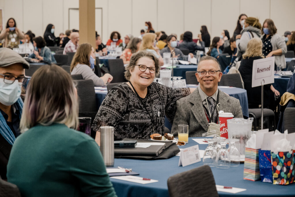 Two participants at the conference smiling at camera.