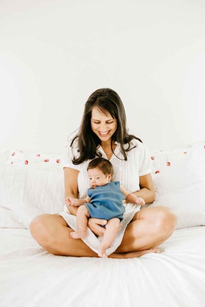 photo of a smiling woman carrying her baby while sitting
