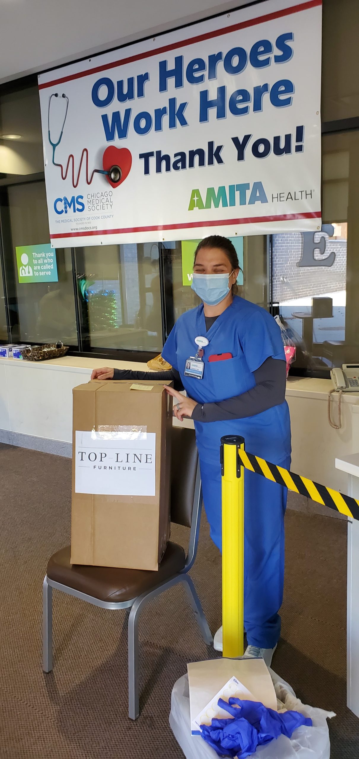 An essential worker from AMITA Health with a packaged face shield donation from Inspire Q. 