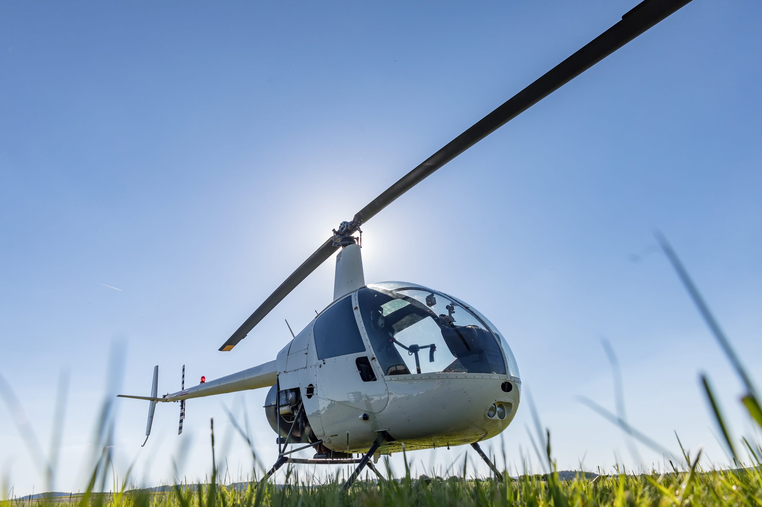 Small Robinson R22 light utility helicopter parked on grass airport. One of the world's most