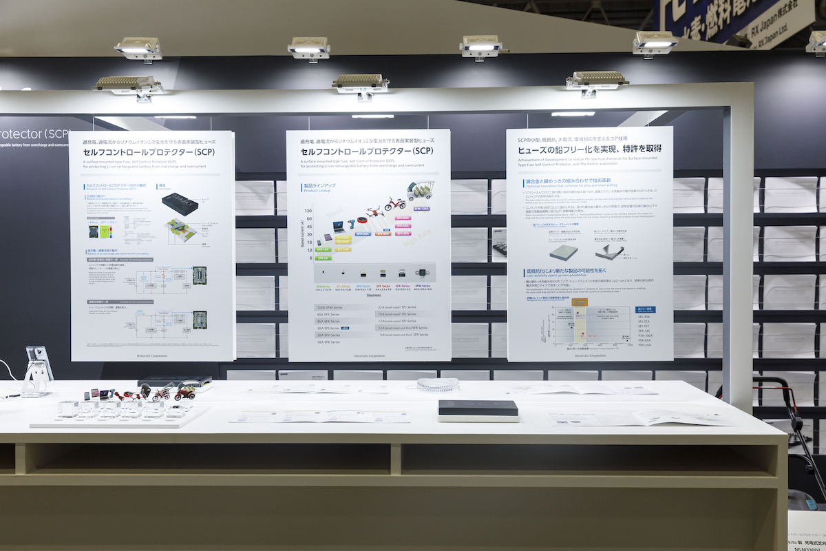 展示台上に吊るしたパネルを指し示して説明｜BATTERY JAPAN SUPER PENGUIN Archives