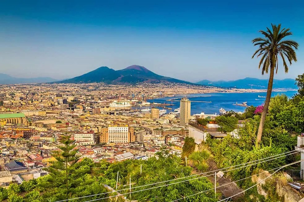 Scenic picture-postcard view of the city of Napoli (Naples) with famous Mount Vesuvius in the background in golden evening light at sunset, Campania, Italy. The best view when spending one day in Naples
