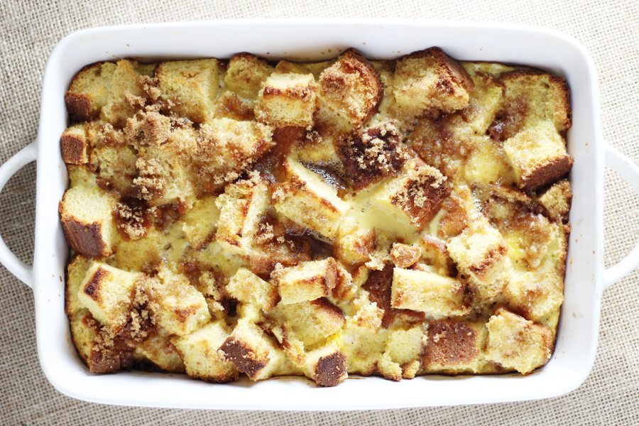 Look at this golden and delicious spiced rum bread pudding. A white baking dish with warm bread pudding