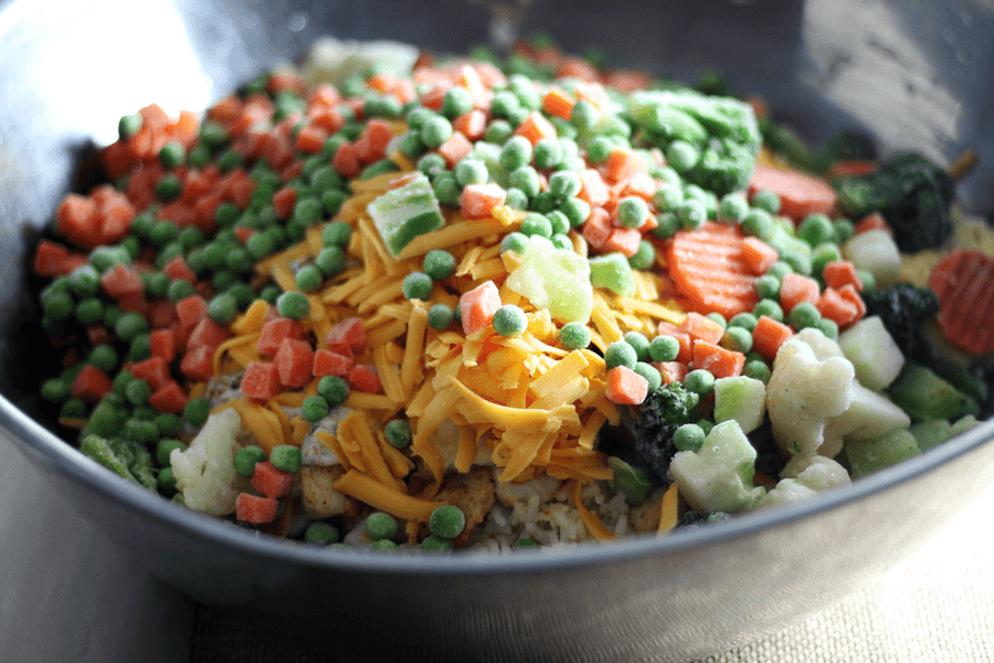 Easy Vegetable Chicken Rice Casserole A bowl of frozen peas, carrots and other chicken rice casserole ingredients.