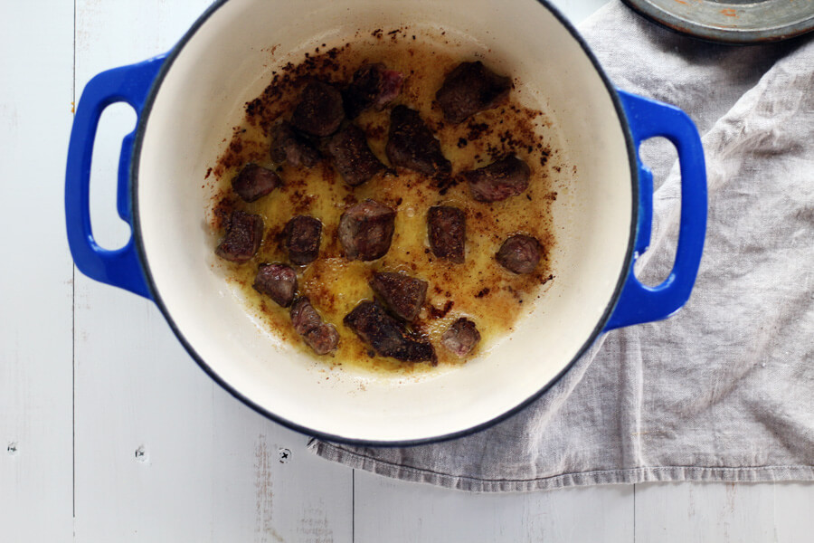 Tip: cook your meat in small batches and do not overcrowd the pan. This allows the meat to brown and builds a base layer of flavor for Irish Stew. Chunks of meat being cooked in a dutch oven.