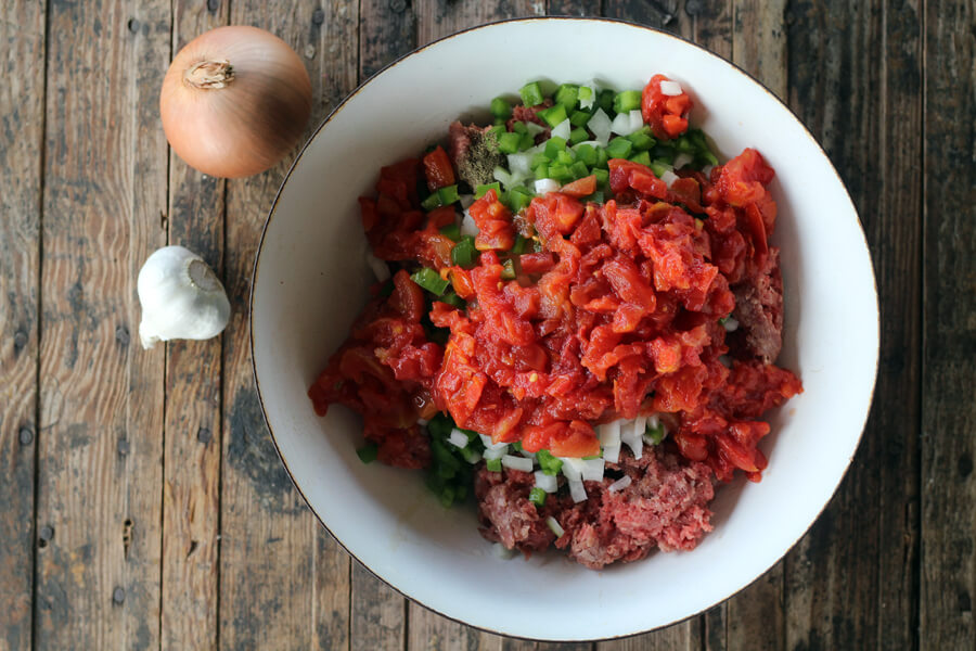 A bowl of ground beef with diced bell pepper, onions, and tomatoes
