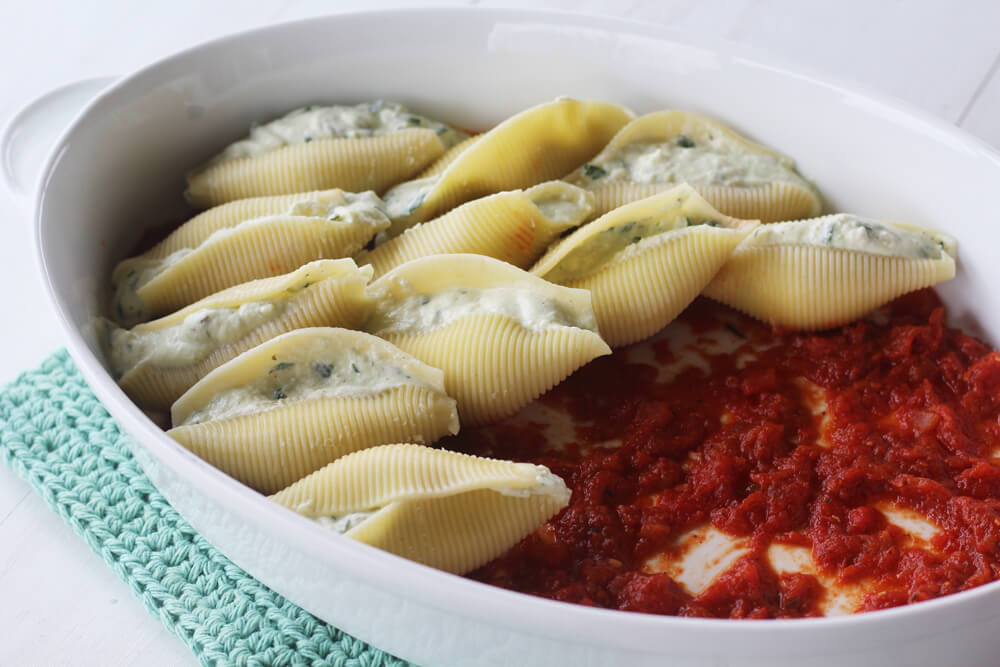 layered stuffed pasta shells on a bed of marinara sauce