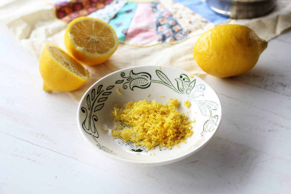 a bowl of lemon zest with lemons in the background