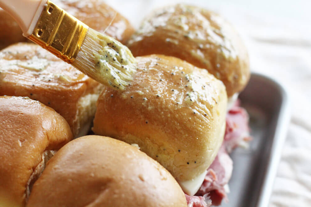 melted butter being brushed on a slider roll