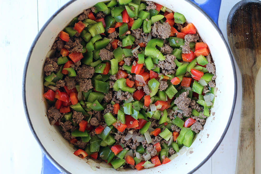red and green peppers in a pot with ground beef and onions