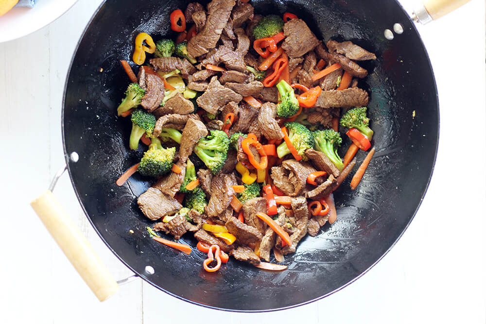 beef, broccoli, peppers, and carrots in a wok