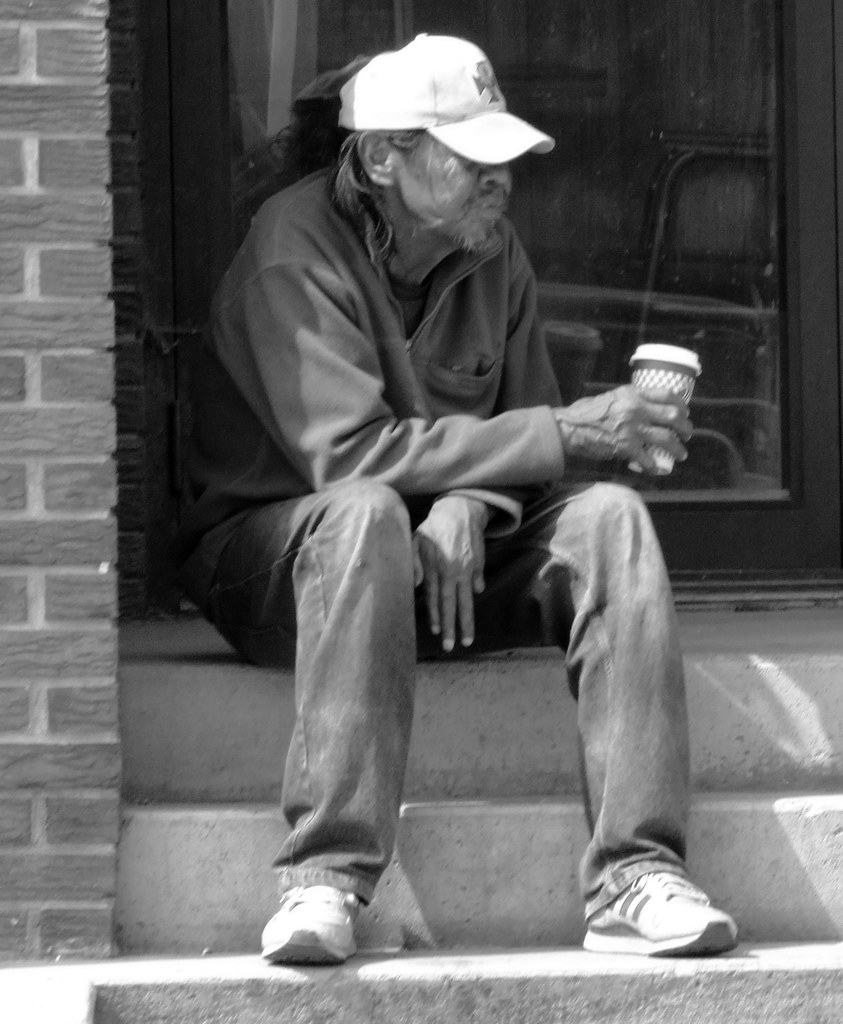 poverty a homeless man sits while drinking coffee that was… Flickr
