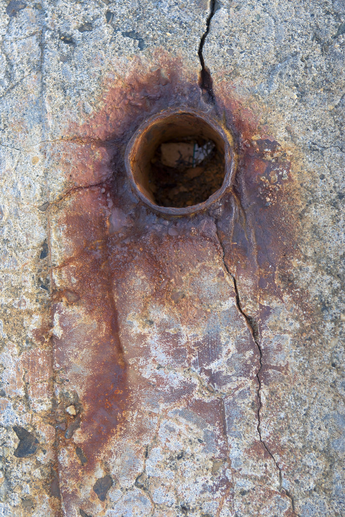 Rusted metal pipe in cracked concrete An interesting color… Flickr