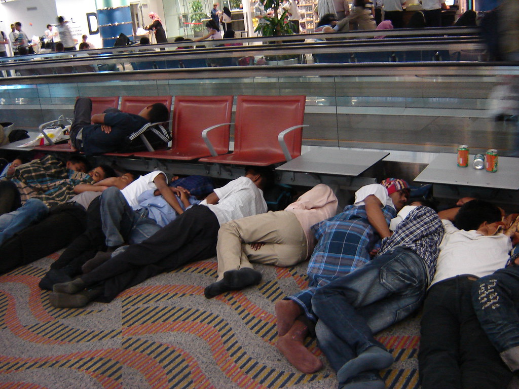 Sleeping travellers at Dubai International Airport, not a