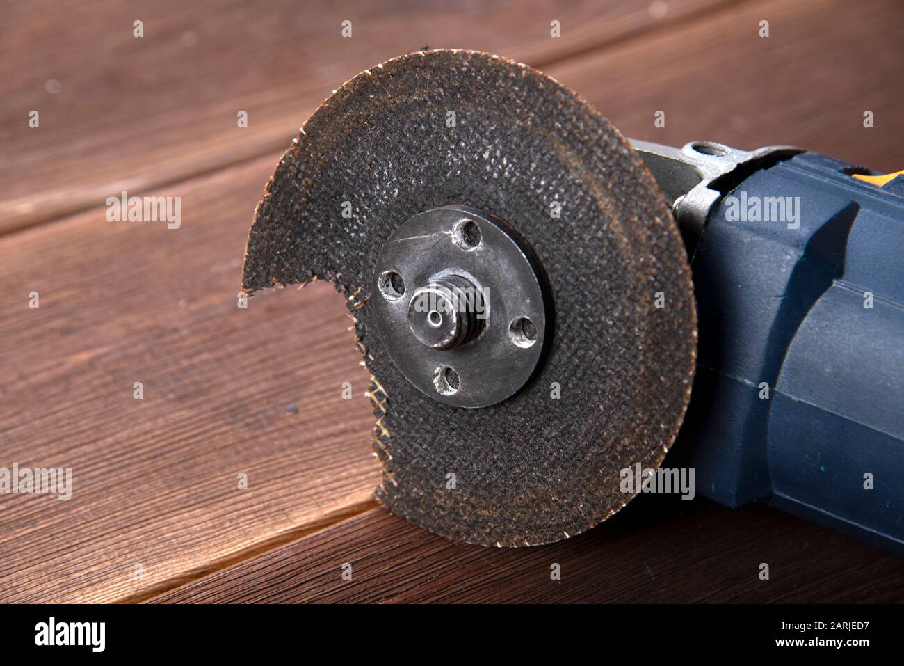 A grinder with a broken blade on a wooden table. The danger of using
