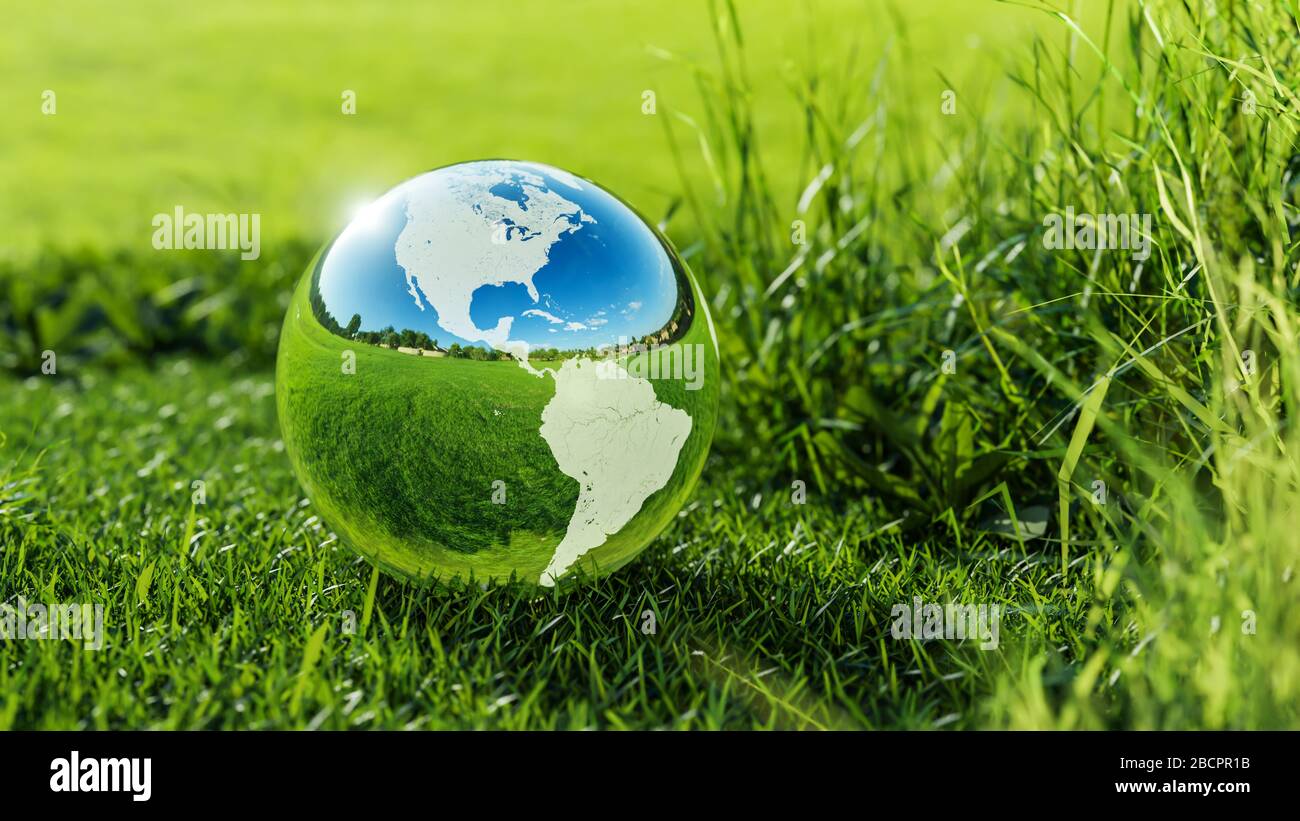 Environment concept. View of glass earth globe in the green grass field