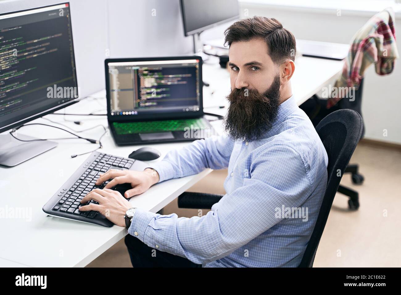 Serious computer programmer developer working in IT office, sitting at