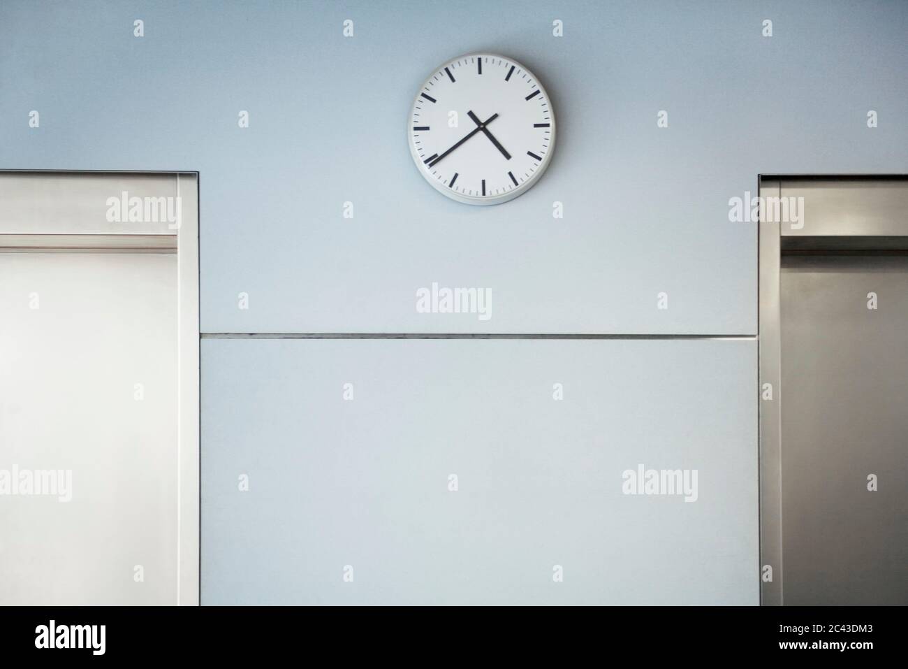 Clock between two elevator doors Stock Photo Alamy