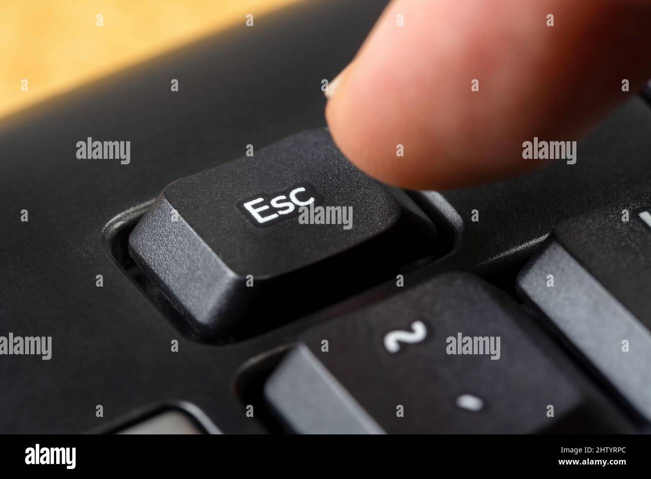Man pressing the escape key on a simple black office keyboard, finger