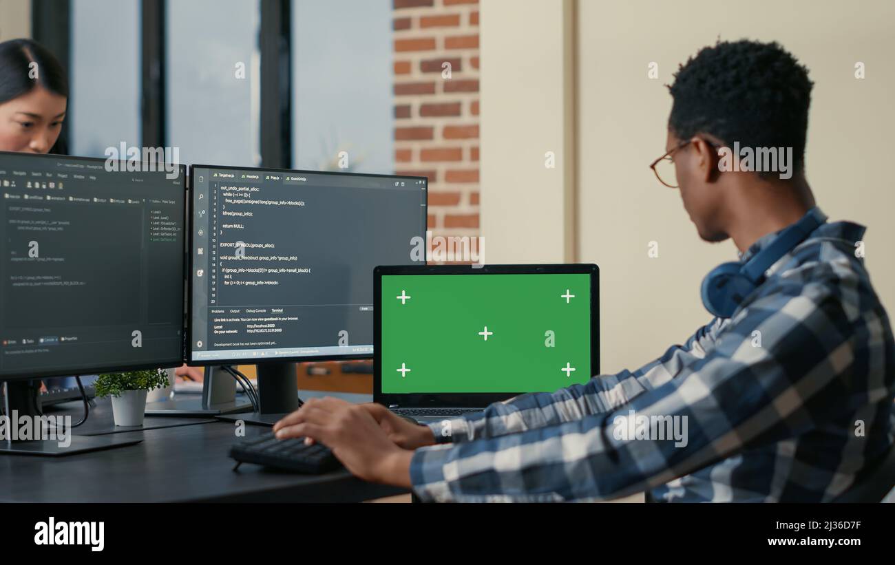 Software developer writing code using computer keyboard and laptop with