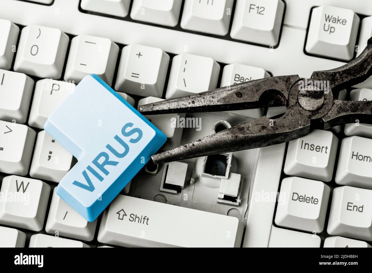 Pliers with removed blue VIRUS key from a computer keyboard. Computer