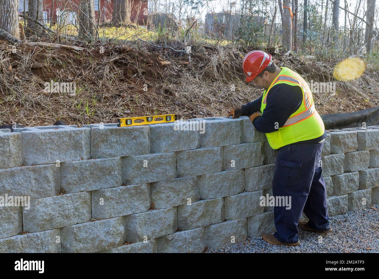 Man leveling tool building retaining concrete block wall with being