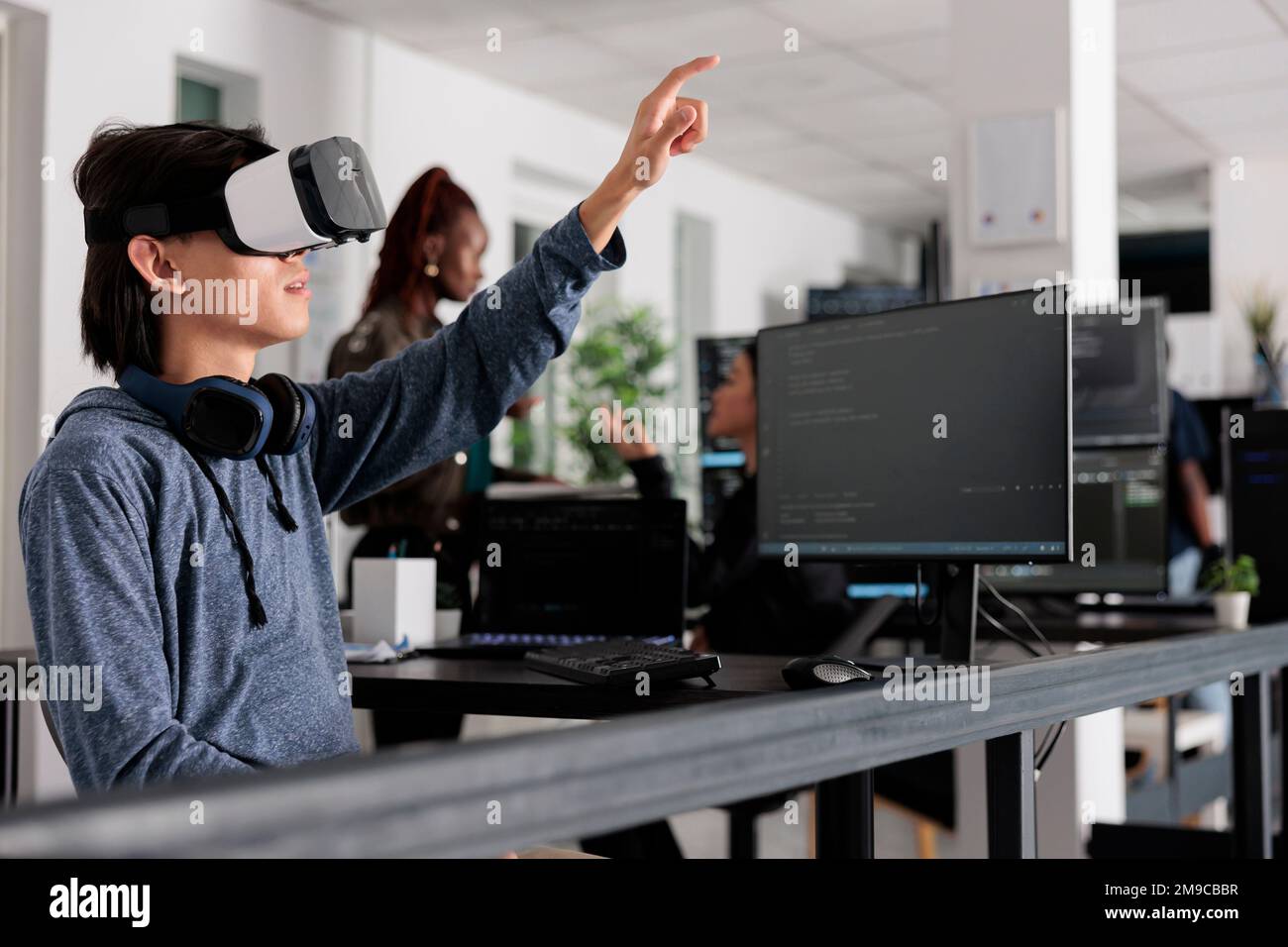 Asian software developer using virtual reality goggles to code new
