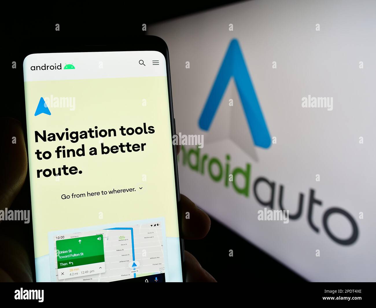 Person holding smartphone with webpage of mobile app Android Auto
